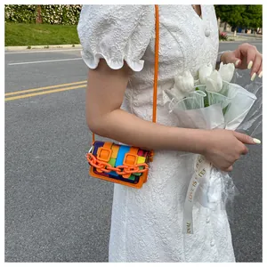 Close-up of a mini multicolor patchwork crossbody bag with bright orange chain and strap