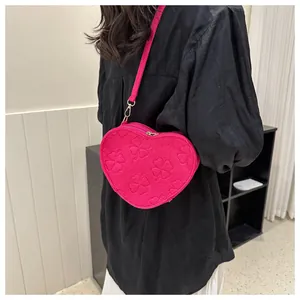 Detail of fuchsia heart-shaped crossbody bag with embossed clover patterns and gold hardware