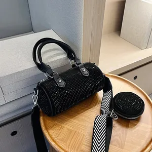 Detail view of black rhinestone cylinder bag with wide strap and round coin purse on wood