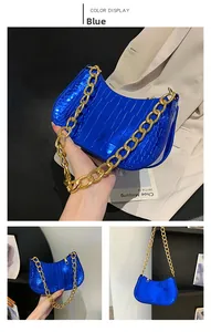 Close-up of blue faux crocodile leather bag with thick gold chain and glossy finish
