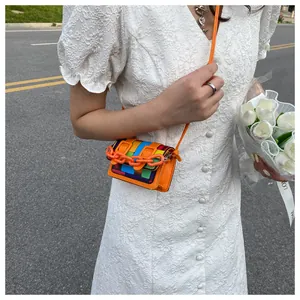 Mini crossbody bag with colorful woven texture and bright orange plastic chain detail