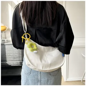Sac bandoulière en toile blanche en forme de croissant avec charm fleur sur modèle