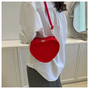 Close-up of red heart-shaped crossbody bag with clover embossing and gold zipper detail