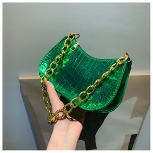 Detail of glossy green crocodile pattern shoulder bag with a thick gold chain handle