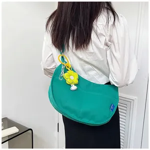 Sac bandoulière vert forêt en toile avec breloque fleur jaune porté par un mannequin