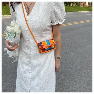 Detailed outdoor shot of a colorful mosaic mini crossbody bag with orange acrylic chain