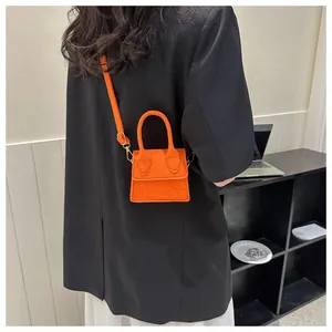 Detail van een feloranje mini-crossbodytas met krokodillenprint bij een model