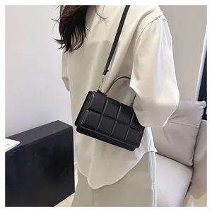 Vue latérale détaillée d'un sac bandoulière en cuir noir matelassé avec finitions dorées