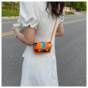 Outdoor shot of a mini crossbody bag with rainbow mosaic pattern and orange chain strap