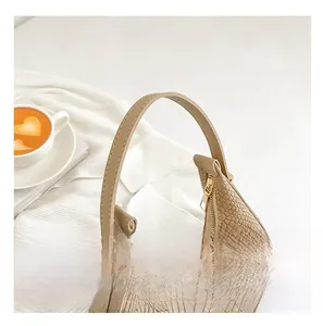 Detail of light brown crocodile pattern texture and handle stitching on shoulder bag