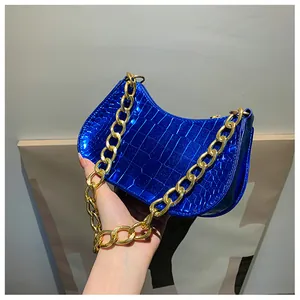 Close-up of vibrant blue crocodile-embossed leather baguette bag with thick gold chain