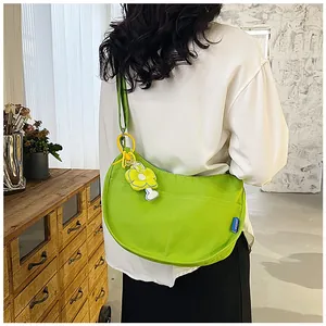 Détail d'un sac bandoulière demi-lune en toile vert vif avec un charm fleur jaune