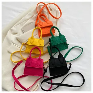 Platte lay van vijf mini-crossbodytassen met krokodillenreliëf in felle kleuren op blazer
