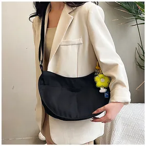 Détail du sac demi-lune noir en toile avec bandoulière réglable et pendentif fleur jaune