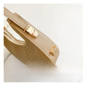Detailed close-up of golden metal buckle and faux crocodile texture on beige bag