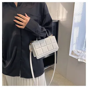 Gros plan d'un sac bandoulière blanc matelassé avec boucles dorées sur mannequin