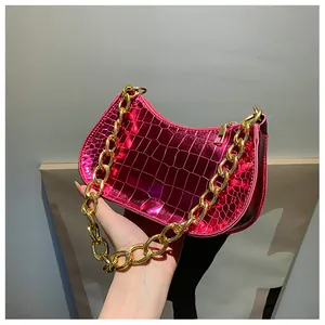 Close-up of metallic pink crocodile embossed leather texture and chunky gold chain strap