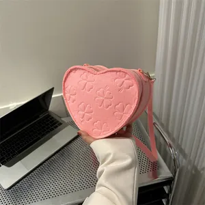 Detailed view of pink heart-shaped crossbody bag with clover embossed texture and strap