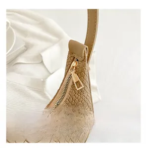 Detailed macro view of the smooth golden zipper and crocodile texture on the camel bag
