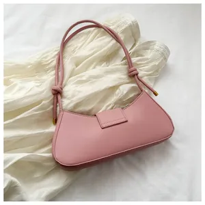 Dettaglio della borsa sottobraccio rosa cipria con cinturino annodato e finiture dorate