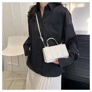 Détail du sac à bandoulière matelassé blanc avec ferrures dorées porté par un mannequin