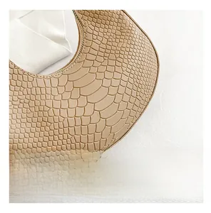 Detailed close-up of beige crocodile pattern texture and golden zipper on hobo bag