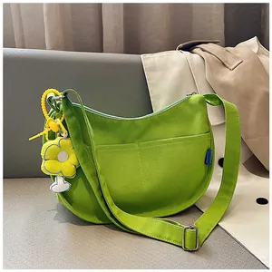Détail du sac bandoulière en toile verte avec breloque fleur jaune et sangle