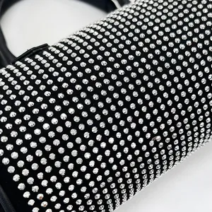 Close-up of sparkling rhinestone handbag surface with black leather handle detail