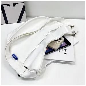 Vue intérieure du sac bandoulière en toile blanche montrant sa grande capacité de rangement