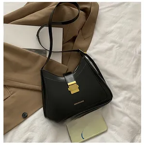 Chic black bucket bag with gold clasp and fashion text, shown with phone for size scale