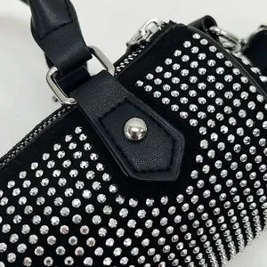 Macro detail of black suede handbag featuring shimmering silver rhinestones and metal zipper