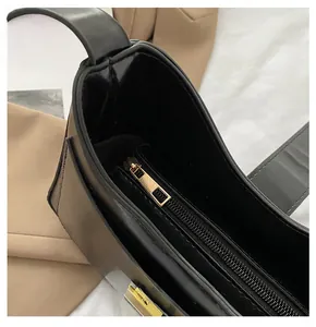 Detail of smooth gold metal zipper on minimalist black leather shoulder bucket bag