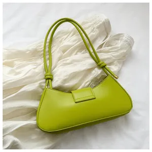 Dettaglio di una borsa sottobraccio verde neon con finitura lucida e nodo elegante