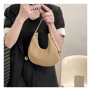Detail of beige hobo bag with crocodile texture held by a model in a black suit