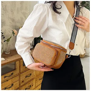Détail du sac bandoulière en daim marron avec clous argentés et sangle à chevrons