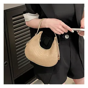 Close-up of beige crocodile pattern underarm bag on a model wearing a black blazer