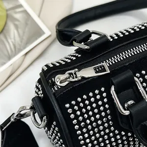 Top macro view of black leather handbag featuring silver studs and metallic zipper detail