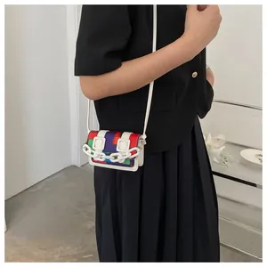 Close-up of mini crossbody bag with colorful mosaic patchwork and bold white chain link strap