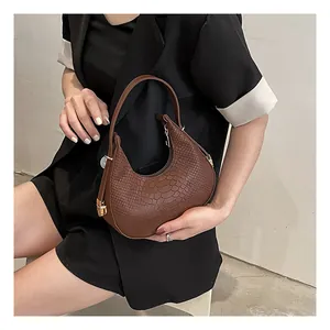 Detail showing brown crocodile-embossed texture on semi-circular shoulder handbag