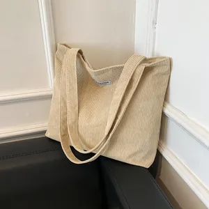 Detailed texture of beige corduroy shoulder bag with fashion label and long straps