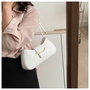 Primo piano di una borsa sottobraccio in pelle bianca con fibbia metallica dorata curva