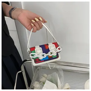 Close-up of geometric color block mini bag with white plastic chain and buckle straps