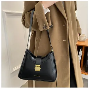 Detail of black leather shoulder bag with golden square buckle and fashion logo text