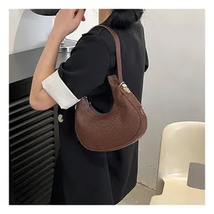 Close-up of dark brown crocodile embossed leather shoulder bag with gold metal buckle
