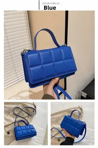 Détail d'un sac à main bleu matelassé avec poignée structurée et texture rembourrée