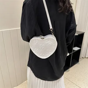 White heart-shaped crossbody bag with clover embossed texture and gold hardware