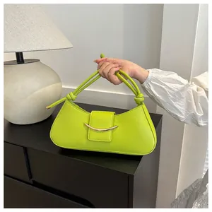 Dettaglio della borsa a mezzaluna verde lime con fibbia dorata e manico a corda annodata