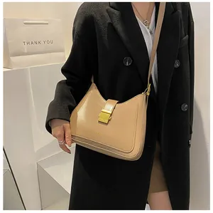 Detail of light brown leather bucket bag featuring a square gold buckle on a model