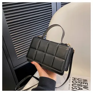 Détail du motif matelassé et de la boucle dorée sur le sac à main noir en simili cuir