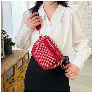 Détail du sac bandoulière rouge avec strass et une large sangle rayée noire et blanche